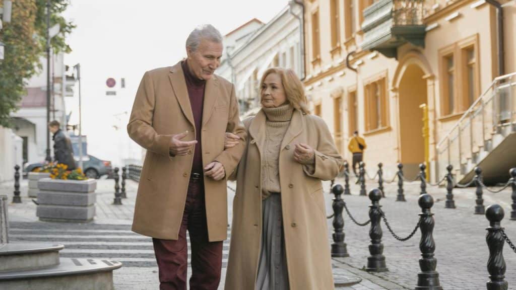 A couple walking arm in arm down a city street in matching coats.
