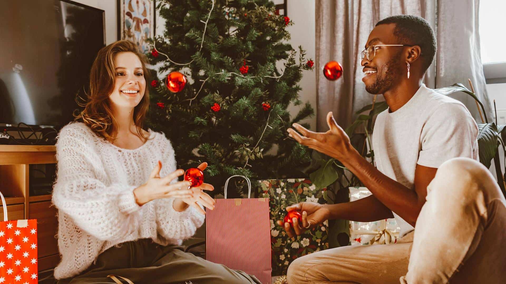 A couple decorating a Christmas tree together.