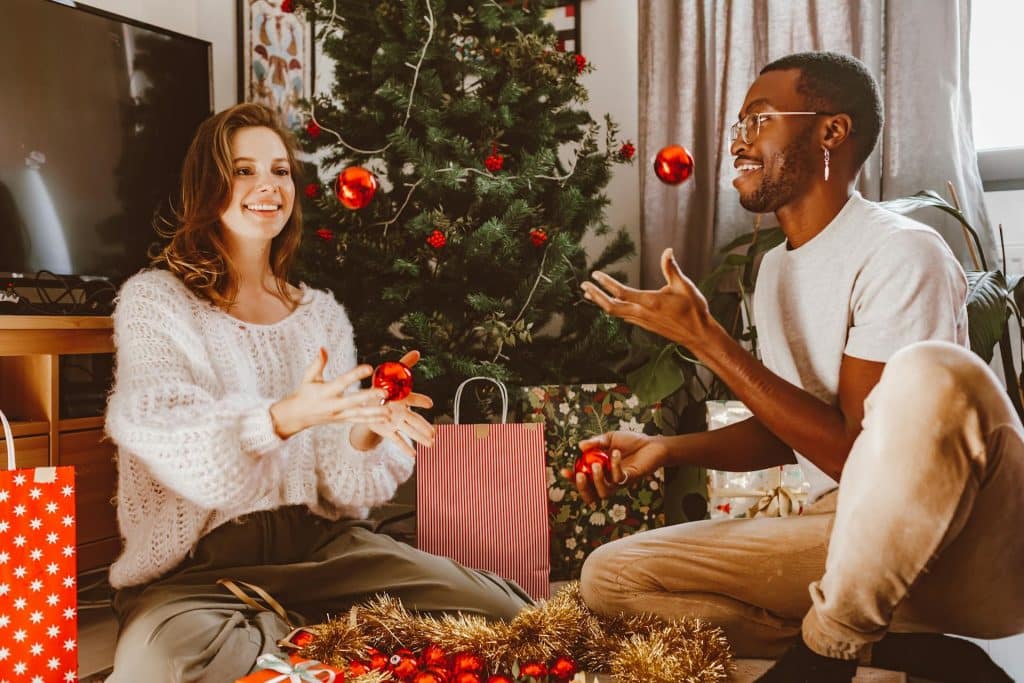 A couple decorating a Christmas tree together.