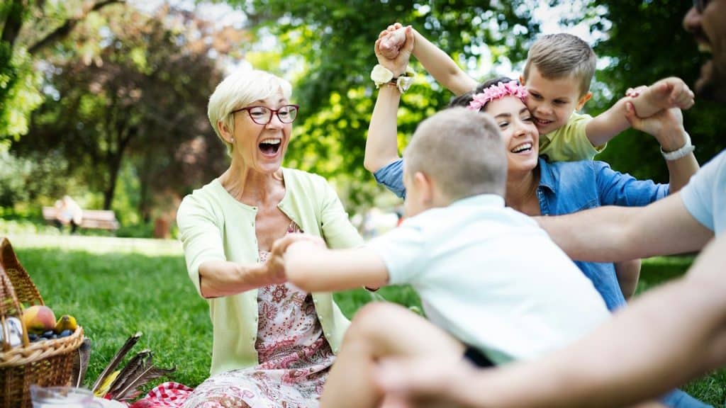 A happy multi-generation family enjoying a picnic in a park.