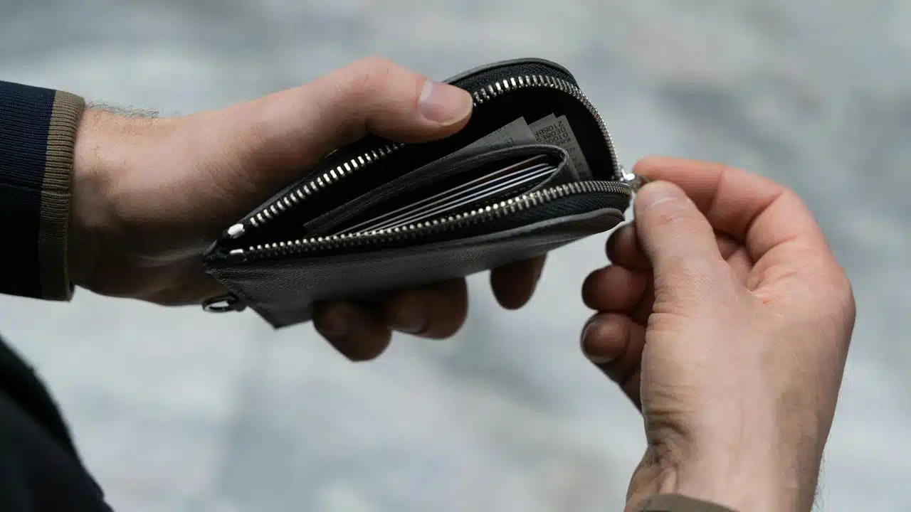 A person opening a black leather wallet.