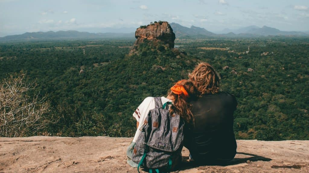 A man and woman sitting beside a cliff.