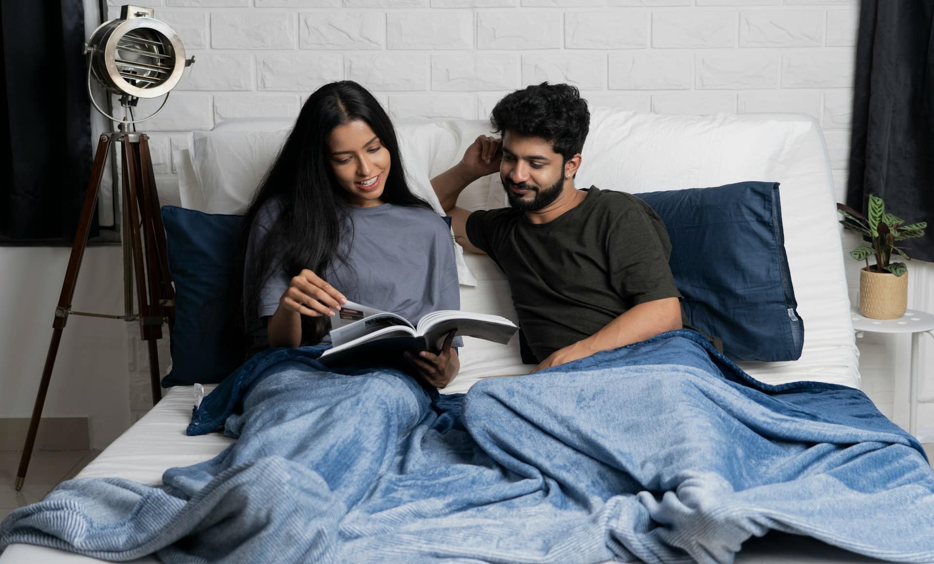 A couple in bed looking at a magazine.