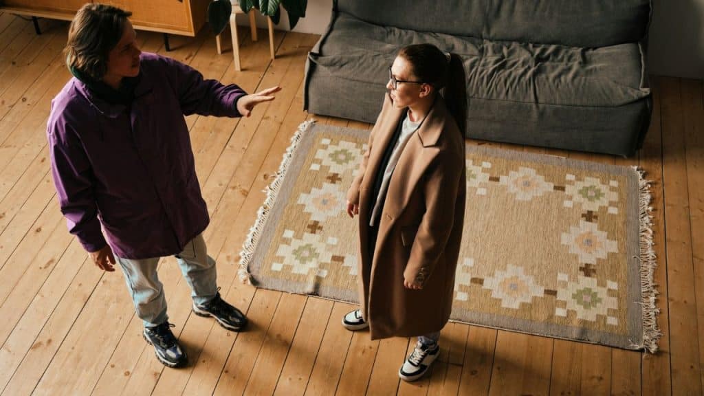 An overhead view of two people arguing in a living room on a wooden floor.