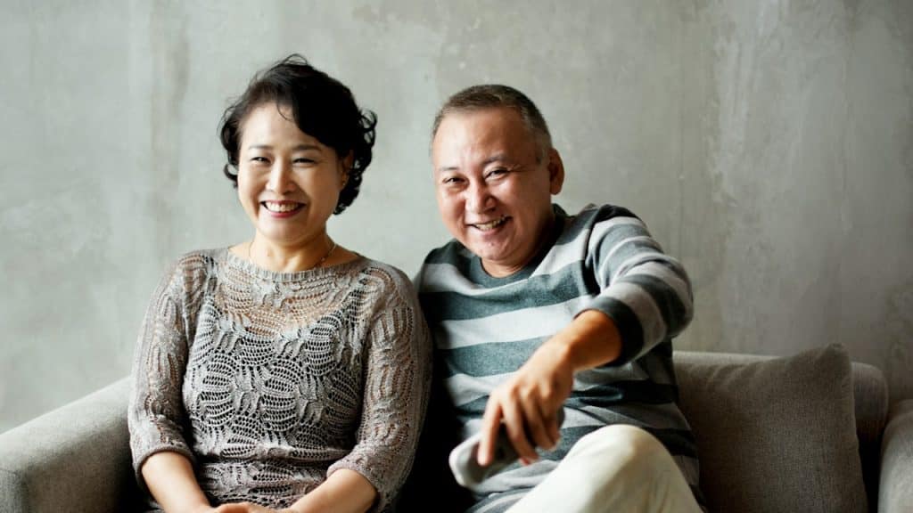 A mature couple sitting on a couch together.