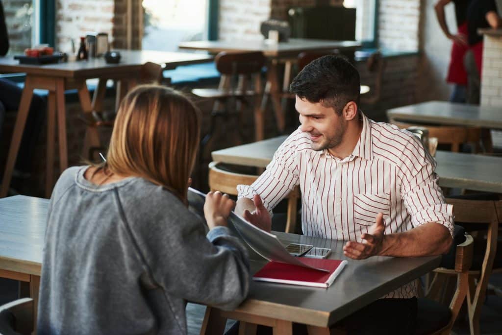 A man talking to the woman at the restaurant.