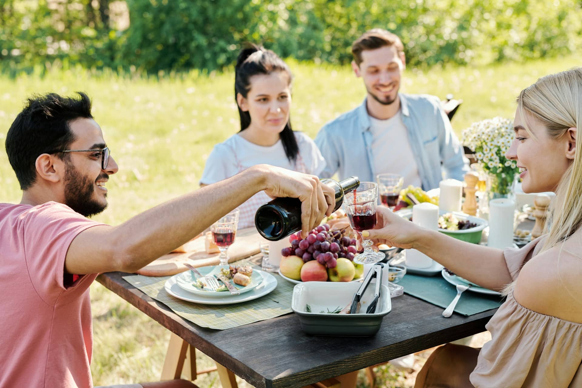 A young man pouring wine into the pretty girl’s wine glass.
