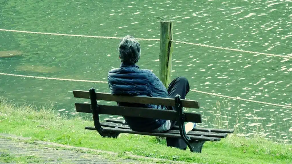 A person sits on a bench by the water.