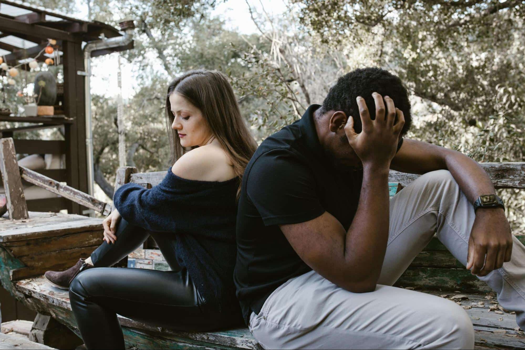 A man and woman sitting back to back 