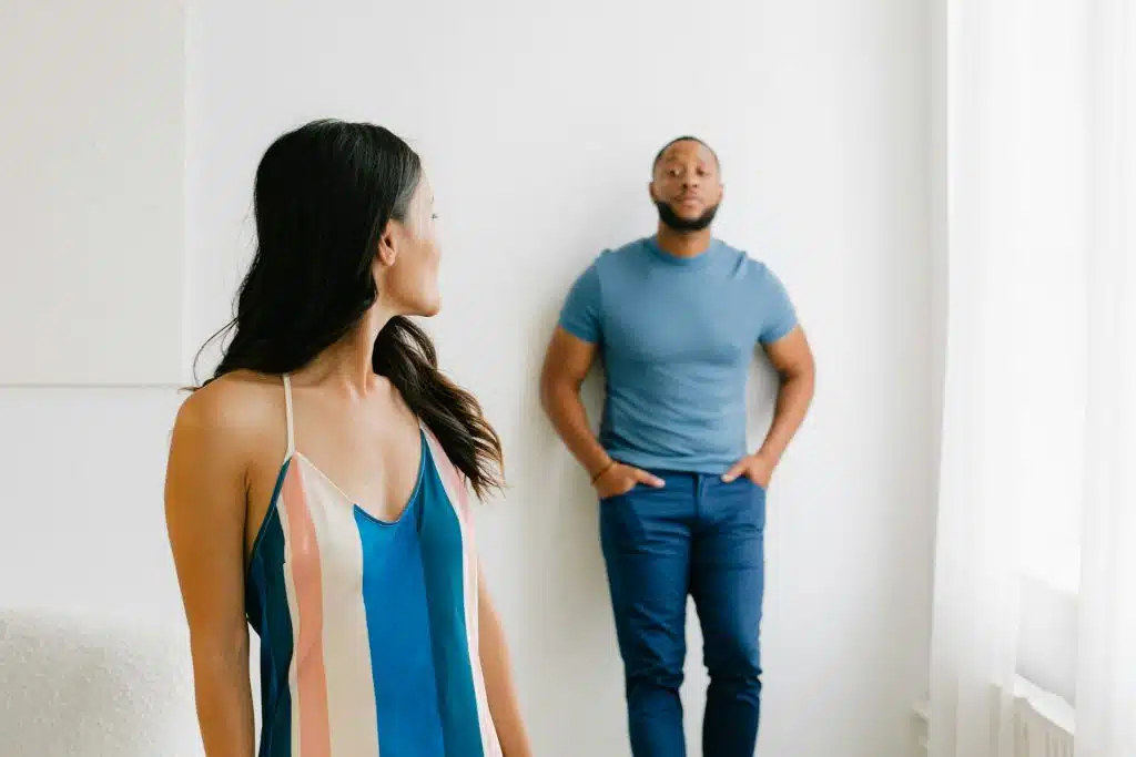 A woman looking at the man leaning against a wall.