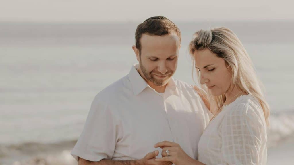 A couple at the beach admiring an engagement ring.