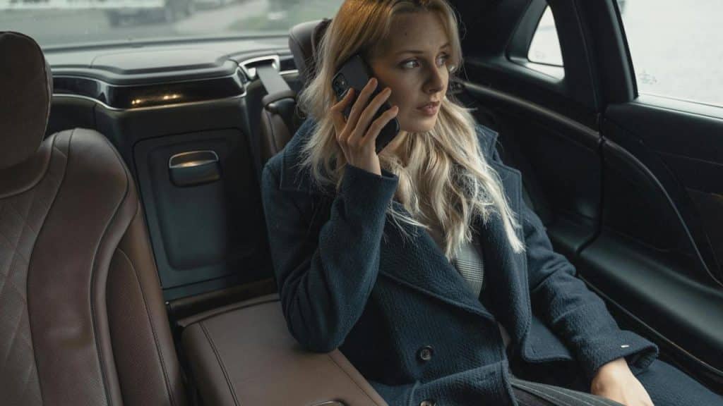A woman sitting in the back seat of a car while talking on a phone.