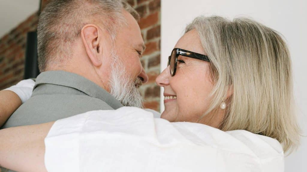 A senior couple embracing and smiling at each other.