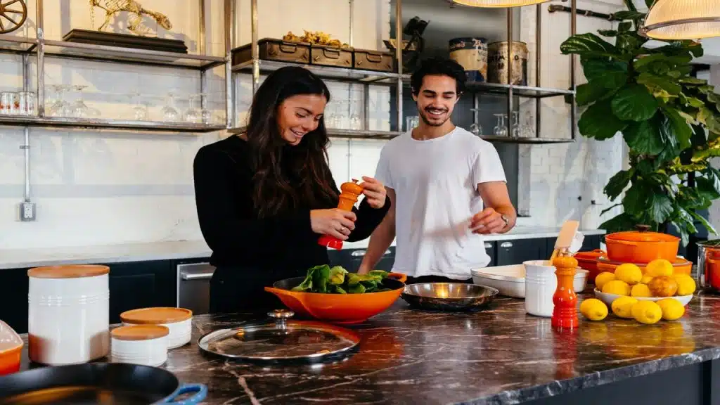 A couple cooking while smiling