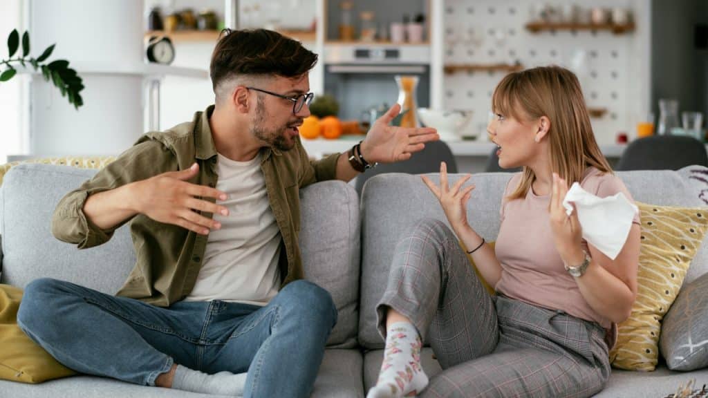 A couple arguing while sitting on a couch.