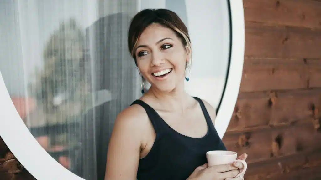 A woman smiling and having coffee.