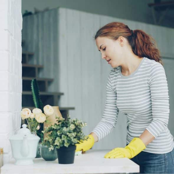 A woman in yellow gloves cleaning a table.