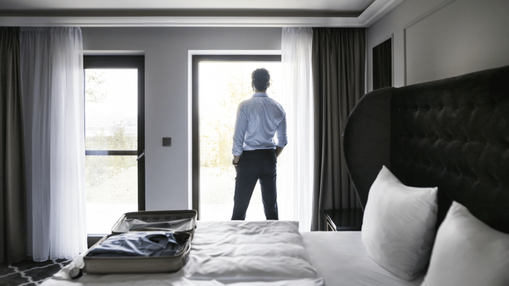 A man looking out the window of a hotel