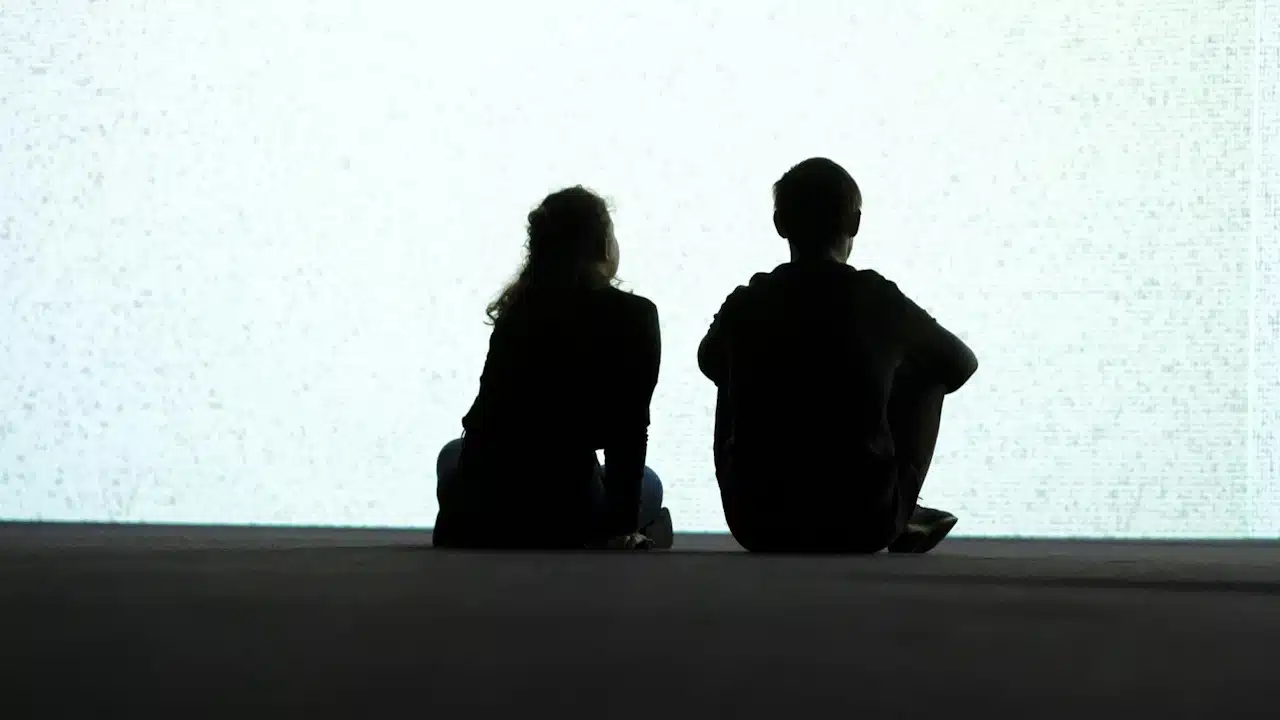 A couple sit and gaze at the bright background. 