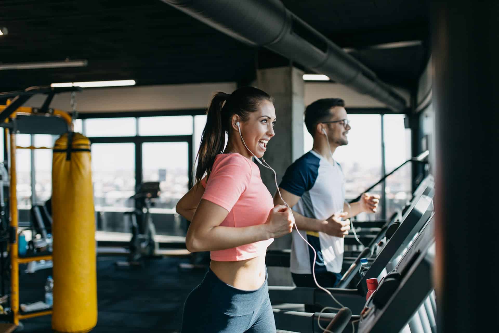 A man and a woman running on a treadmill.