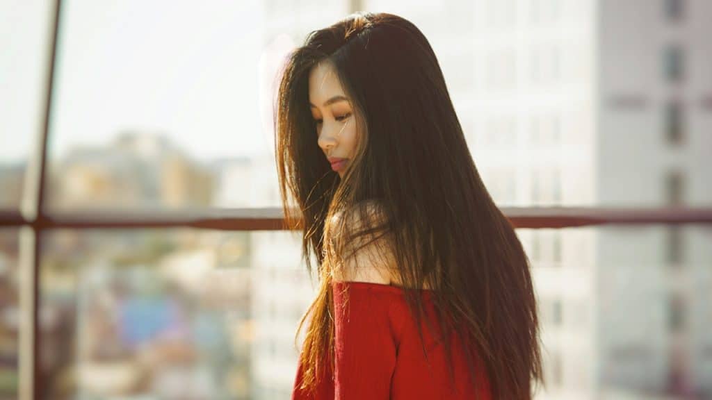 A woman with long hair standing outdoors while looking down.