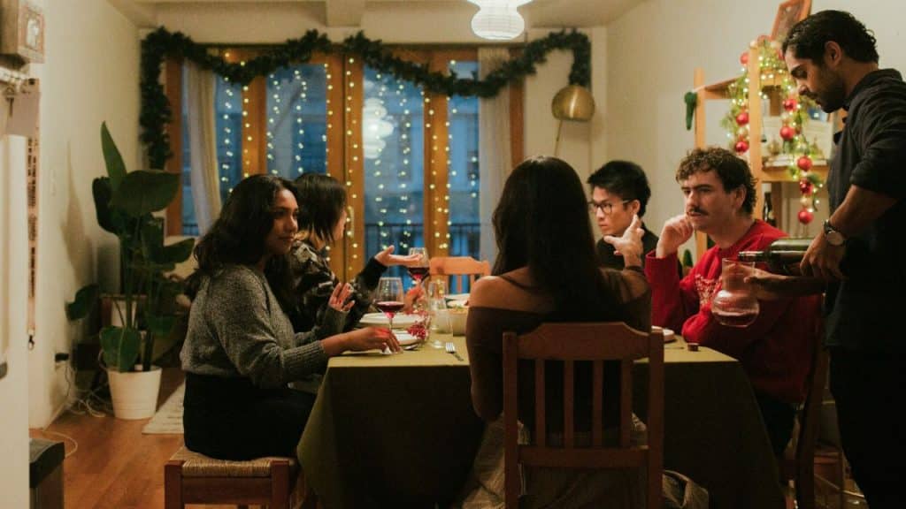 A group of people sitting around a table having a meal with festive decorations.