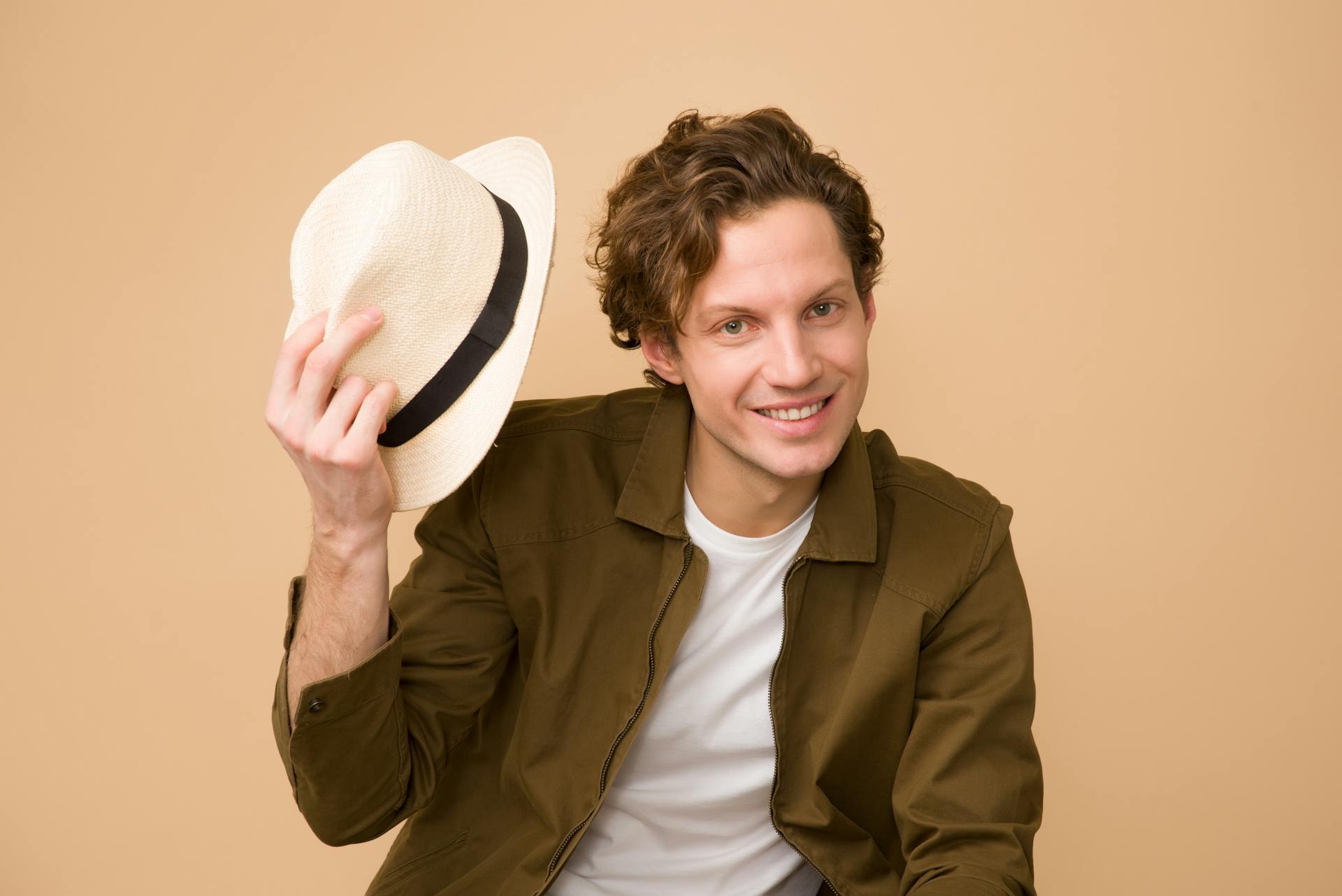 A happy man holding a fedora hat.