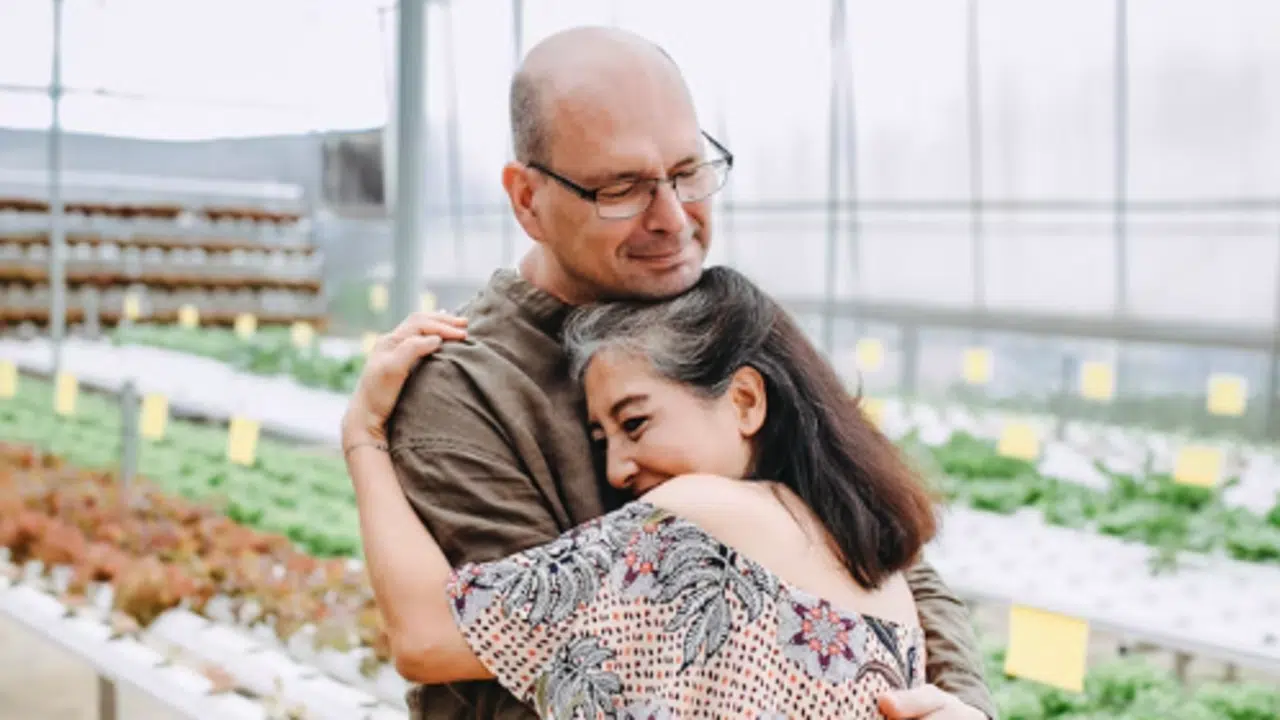 A couple hugging in a greenhouse
