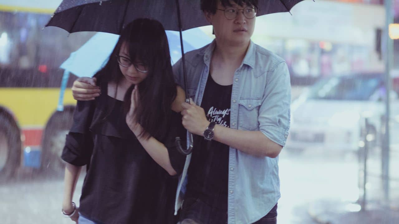 A man holding an umbrella over a woman as they walk together in the rain.