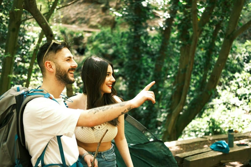 A couple standing in the woods pointing at something.