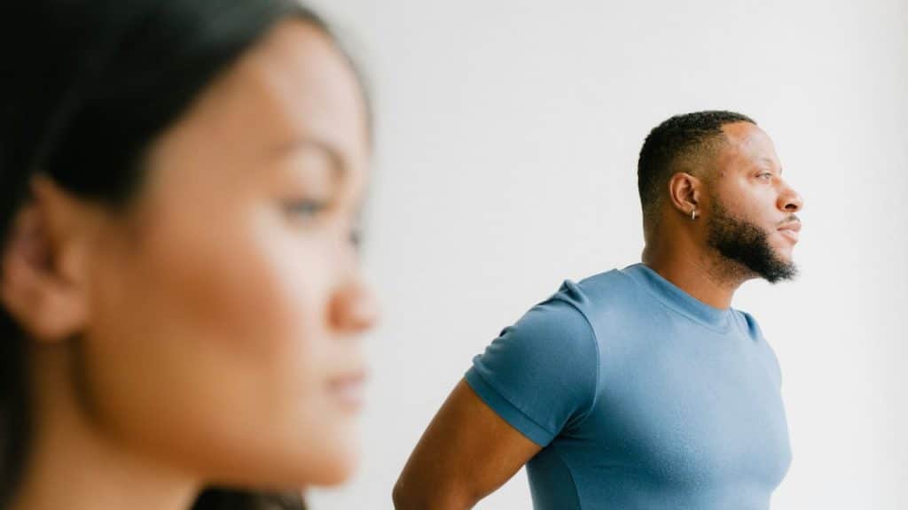 A man in a blue shirt is in profile; a woman is out of focus in the foreground.