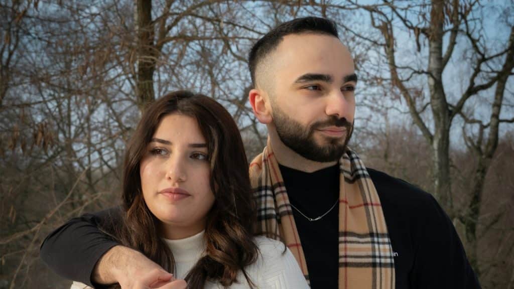 A couple standing close together while looking in different directions.