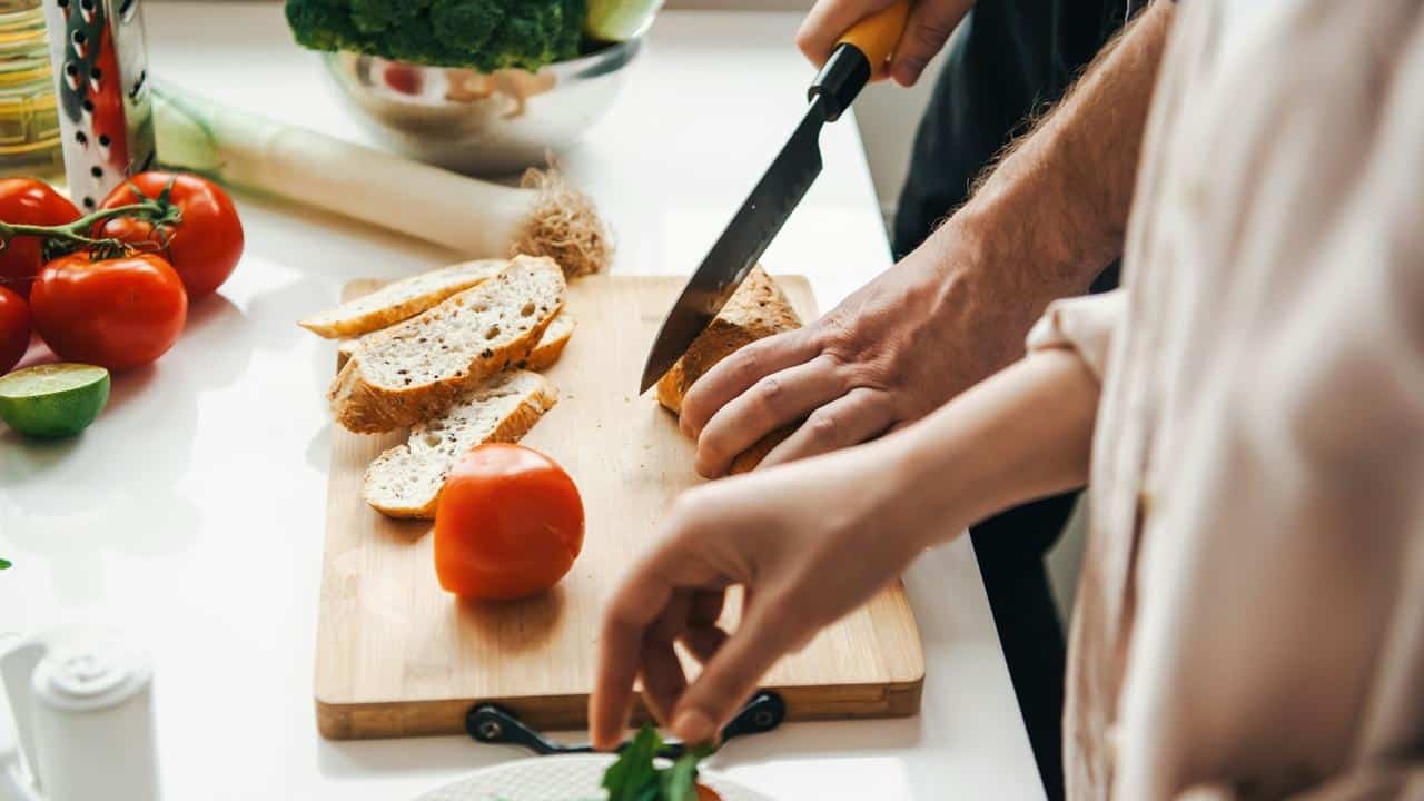 A person slicing bread on a cutting board.