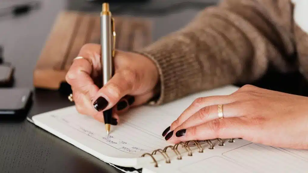 A person using a calculator while holding cash and a pen at a desk.