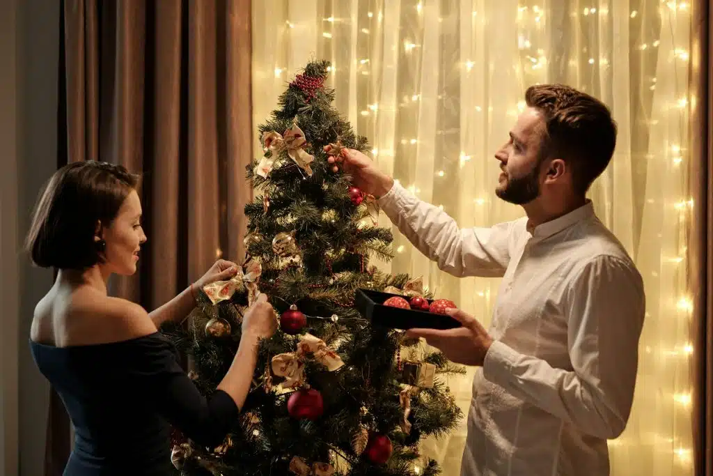 A couple decorating a Christmas tree.