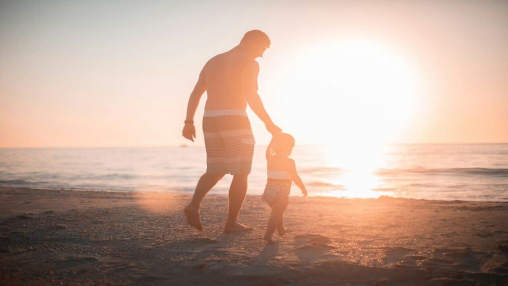 A man walking with his kid at the beach