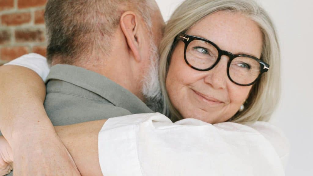 A woman smiling softly while hugging someone close.