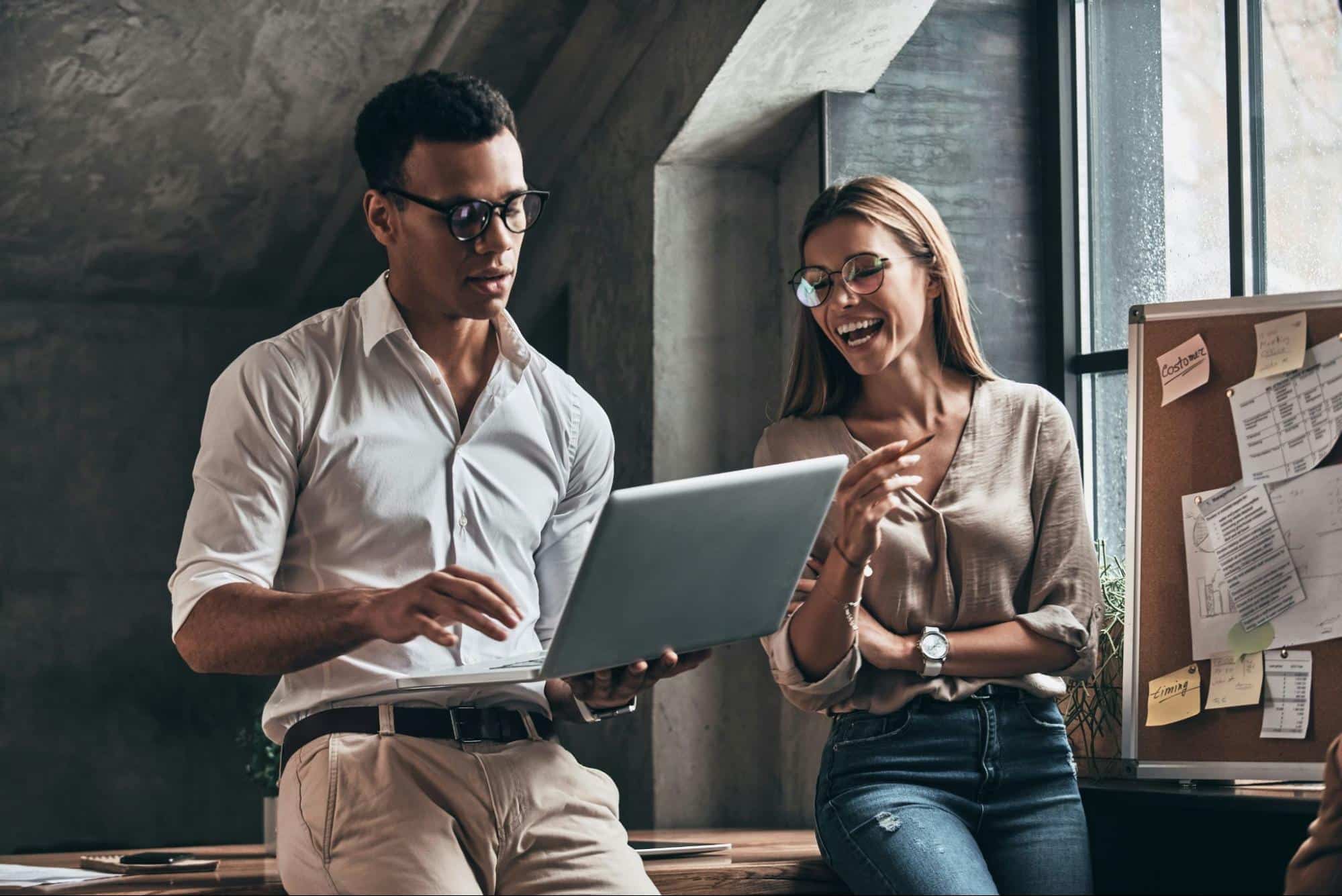A man holding a laptop and a woman beside him