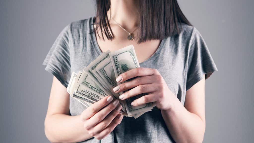 Woman holding US hundred-dollar bills.