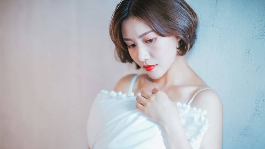 A woman in a white dress is holding a cushion.