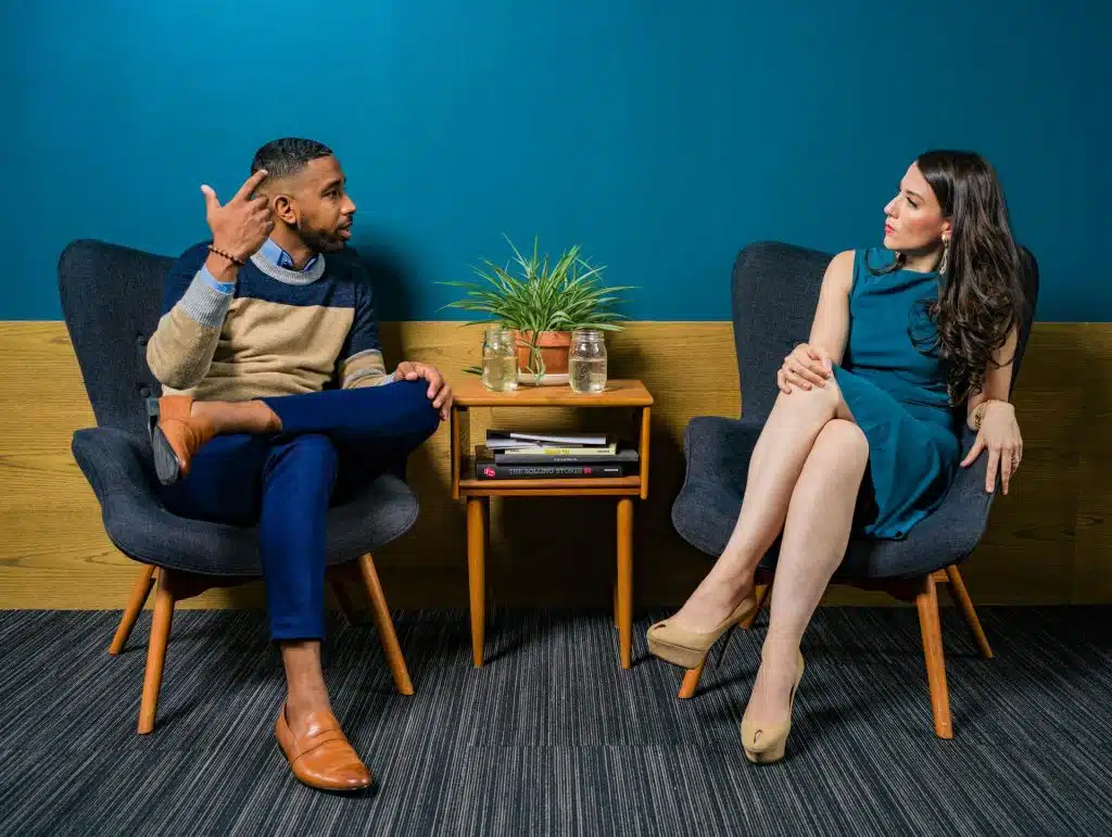A man talking to the woman wearing a teal dress.