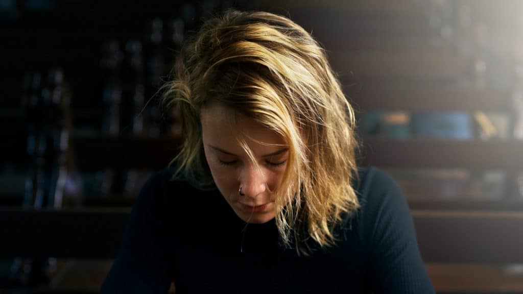 A sad blonde woman gazing downwards.