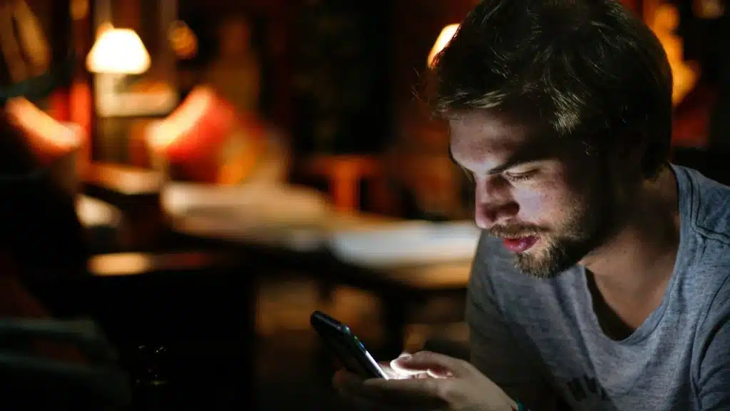 A bearded man looking at his phone’s screen.