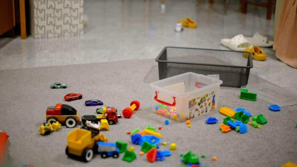 An indoor carpeted floor scattered with colorful building blocks and toy vehicles.