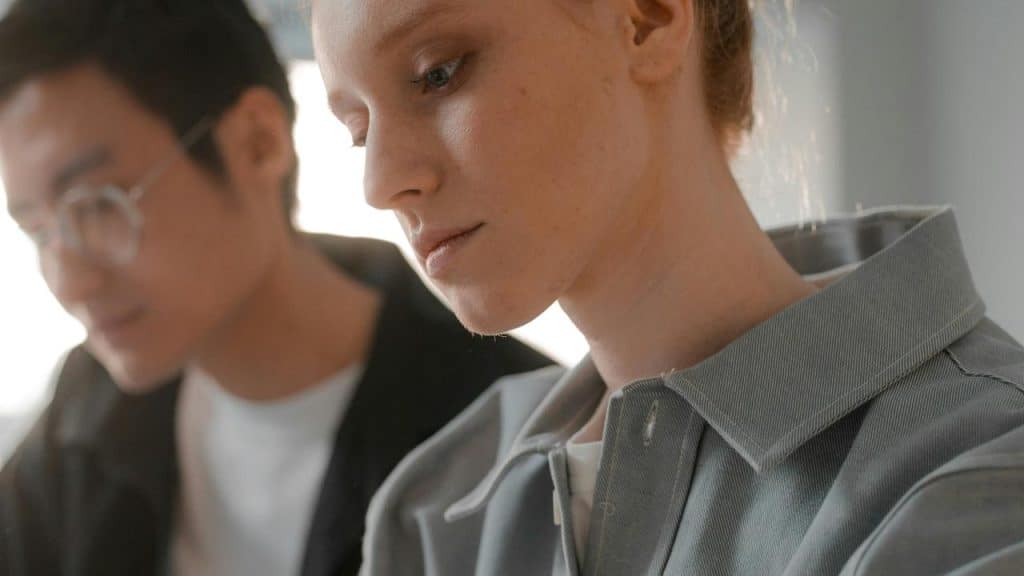 A woman focused on work beside a blurred colleague