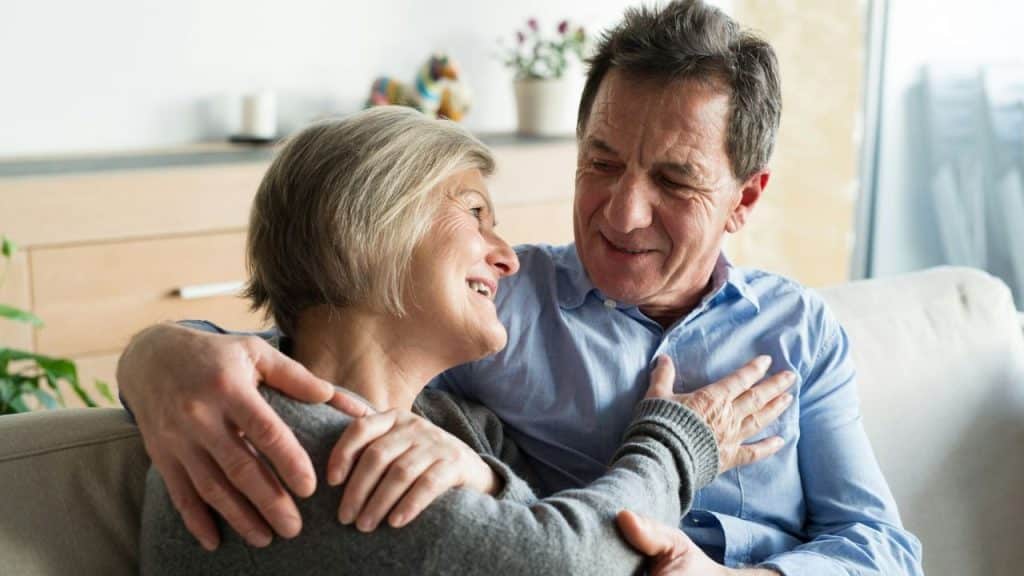 Older couple embracing on a couch, looking at each other and smiling.