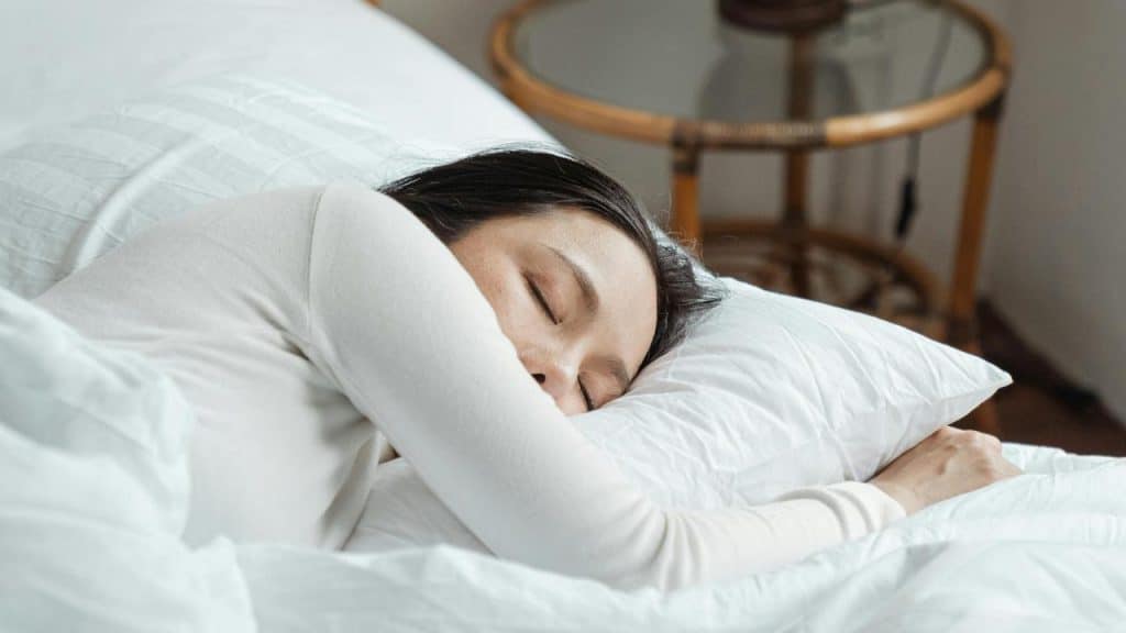 A woman peacefully sleeping on a bed with her head on a pillow.