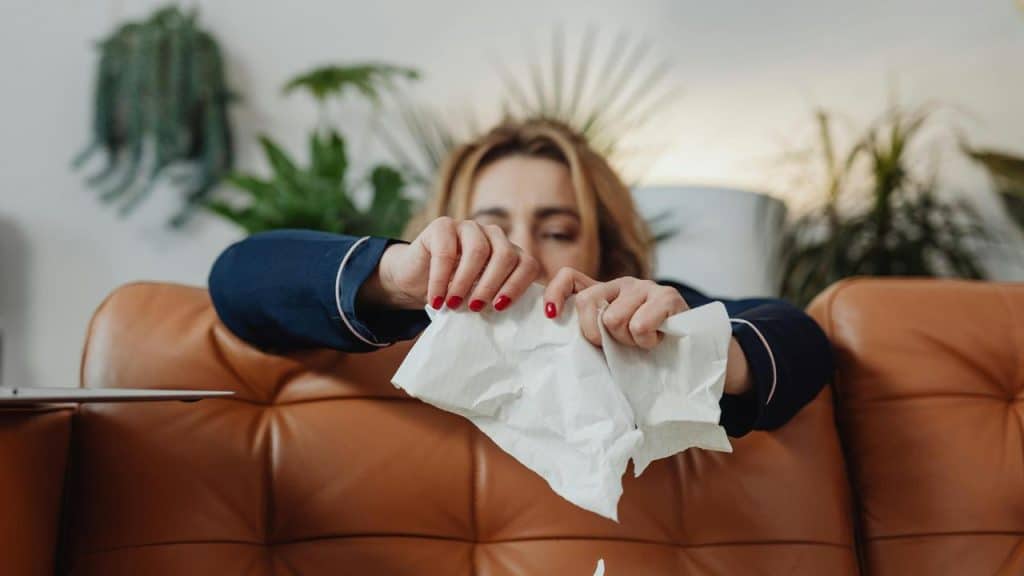 A woman tearing a piece of paper while sitting on a couch.