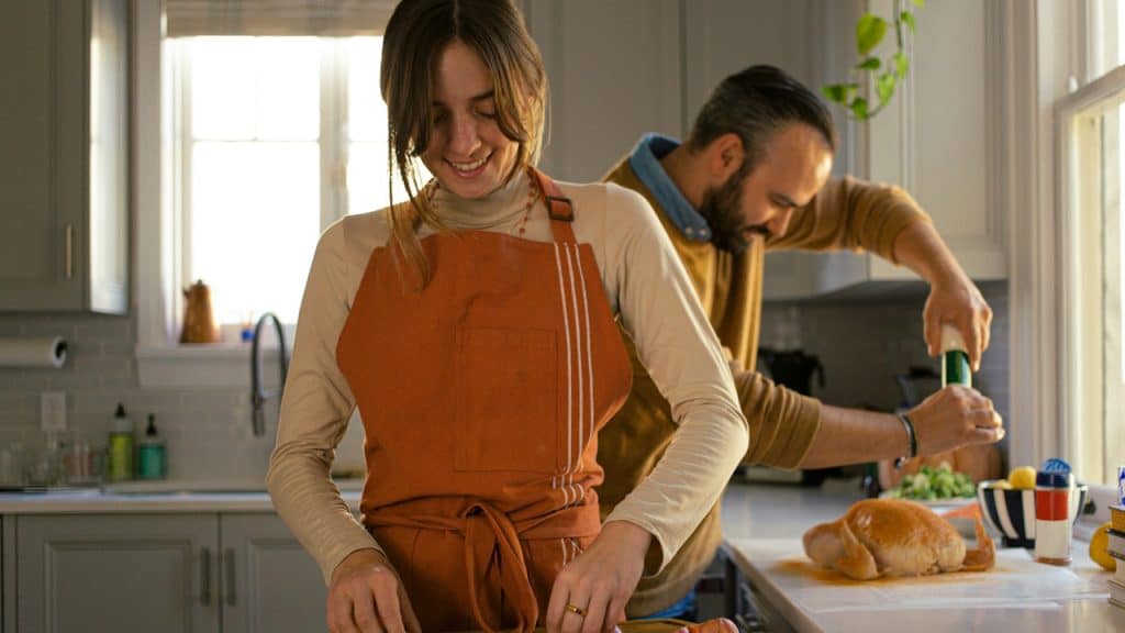 A man and a woman preparing food in a kitchen.