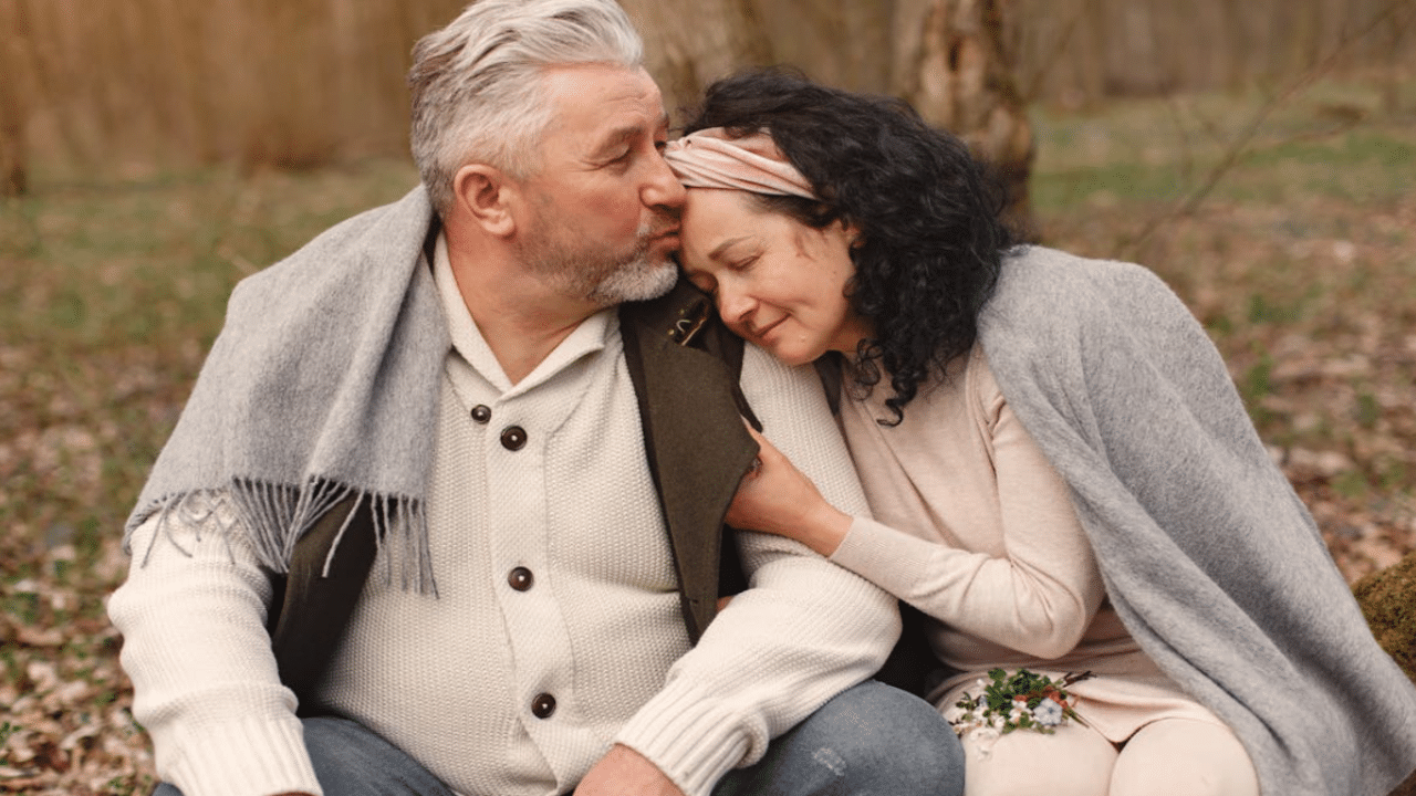 A man giving his wife a forehead kiss